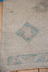 Textured detail showing ivory and powder blue diamond pattern on a distressed Oushak rug.