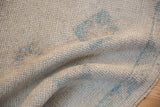 Distressed Oushak rug pile with visible knot heads, ivory and faded powder blue motifs.