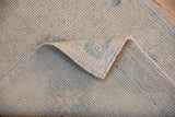 Texture of distressed Oushak rug showing worn pile, visible foundation, and secured side selvage.