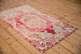 Distressed vintage Oushak rug showing cinnabar red abrashed ground and ivory floral border.