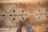Vintage distressed Oushak runner showcasing repeating stepped geometric patterns and abrashed copper field.