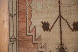 Distressed vintage Oushak runner: textured pile, geometric sand border, machine bound side.