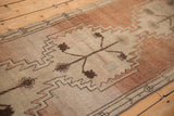 Vintage distressed Oushak runner: abrashed copper-sandalwood field with geometric floral motifs, stepped contours.