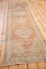 Distressed Oushak runner showing low pile, mostly even wear, and faded pale copper motifs.