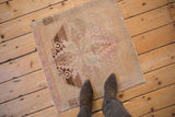 Distressed vintage Oushak rug, faded sand field with fuchsia quatrefoil medallion.