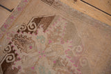 Texture of distressed vintage Oushak rug with abrashed beige field, faded fuchsia patterns, and visible wear.