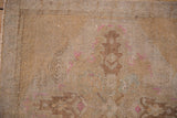 Vintage distressed Oushak rug detail: even wear, faded sand tones, subtle pink motifs, white knots.