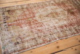 The well-worn, low-pile surface of a distressed Oushak rug in soft blush and ivory tones.