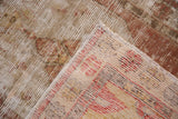 The hand-knotted back and worn, low pile of a distressed Oushak rug's folded corner.