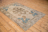 Distressed Oushak rug corner with bright blue spandrel, pale coffee motifs, and wear to knot heads.