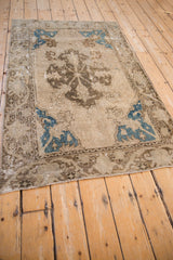 Distressed vintage Oushak corner with blue quarter map spandrel and worn floral border.