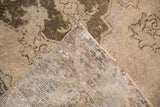 Detail of the vintage Oushak rug's distressed pile, visible foundation, and machine-bound edge.