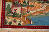 Corner of the vintage pictorial rug with a hand-knotted town, river, and red border.