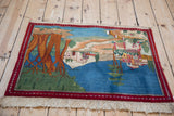 Angled view of the vintage pictorial Kashan rug showing its full town and river landscape.