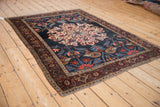 Angled view of an antique Kurdish Bijar rug with an oversized medallion and deep navy blue field.