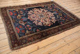 Angled view of an antique Kurdish Bijar rug's oversized roundel medallion on a deep navy field.