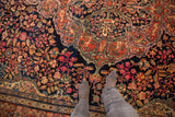 Detailed view of scrolling floral vines with rainbow-like hues on a navy blue antique Farahan Sarouk.
