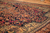 Detailed view of the antique Farahan Sarouk's short pile with colorful arabesques on a navy ground.