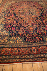 Angled view of an antique Farahan Sarouk carpet's short pile and sprawling floral design on a dark navy field.