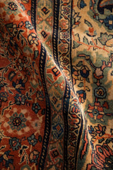 Intricate floral bouquets and scrolling vines in rust, jade, and navy on a hand-knotted antique carpet.