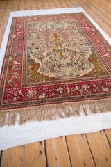 Angled view of a collector's Isfahan rug, showing the Tree of Life design and red border with animals.