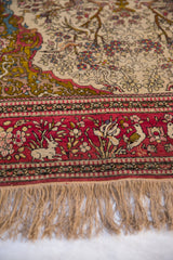 Rabbit and bird motifs in the cochineal red pictorial border of an antique Persian Isfahan rug.