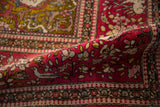 Plush cochineal red pile on a curled antique Isfahan rug, showing a bird and fine floral details.