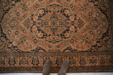 A perspective view of the navy medallion and sandalwood field of a fine antique Mohtashem Kashan rug.