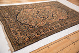 Angled view of a collector Mohtashem Kashan rug's intricate palmette border and lush navy blue pile.