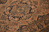 Fine hand-knotted detail of palmettes and floral vines in navy and sandalwood tones.