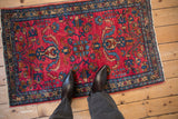 Scale view of a vintage Lilihan rug with a vibrant raspberry red field and intricate floral design.
