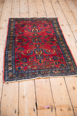 Vintage Lilihan rug from an angle, showing its raspberry red and sapphire blue floral design.
