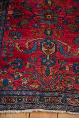 Intricate floral sprays with copper leaves on a vintage Persian Lilihan rug's raspberry field.