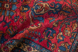 Texture of low pile and scattered white knots on a raspberry red vintage Lilihan rug.