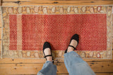 Distressed Oushak runner showing its worn texture and cherry red lattice pattern underfoot.