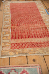 Angled view of a vintage Oushak runner's time-softened texture and red lattice pattern.