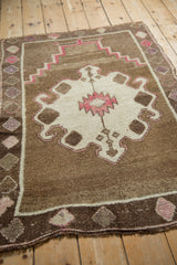 High-angle view of a vintage Kars rug's stepped geometric prayer design in brown, ivory, and pink.