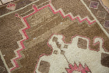 Evenly worn pile on a distressed Kars rug showing geometric motifs in coffee brown and faded raspberry.