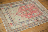 Angled view of a vintage Oushak rug showing its low, even wear and faded geometric borders.