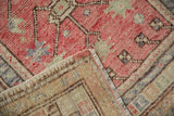 Corner of a vintage Oushak rug showing its hand-knotted back and distressed raspberry pile.