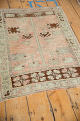 Angled view of a distressed Oushak rug's Tree of Life design in pale rose and brown.