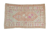 Vintage distressed Oushak rug with a mauve floral medallion on an abrashed slate blue field with decorative borders.