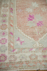 Stepped floral motifs and worn, hand-knotted texture on a vintage distressed Oushak rug corner.
