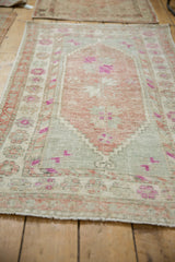 Angled view of a distressed Turkish Oushak rug showing its soft, decorative mauve and slate palette.