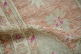 A soft fold in the distressed Oushak rug reveals its hand-knotted pile and muted mauve and silver hues.