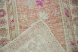 The reverse of a vintage Oushak rug showing its hand-knotted foundation and worn pile.