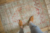 Distressed vintage Oushak rug showing low pile, visible foundation, faded blush and sage green.
