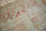 Heavily distressed texture of blush and sage Oushak rug, showing floral motifs and exposed knots.