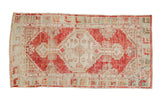 Vintage distressed Oushak rug with a stepped cherry red medallion on an ivory field with pale green accents.