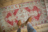 Full overhead view of a distressed Oushak rug showing its faded cherry red and seafoam green colors.